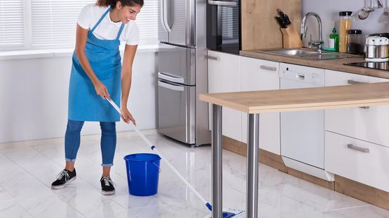 A woman using a mop on a kitchen floor